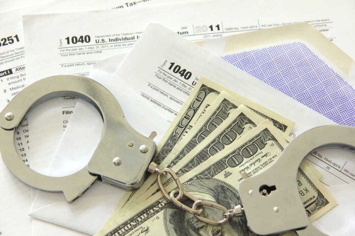 shutterstock_106939859.jpg featured image Handcuffs, dollar bills, and tax forms on a table.