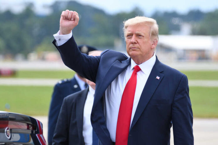 shutterstock_1821865592.jpg featured image Donald Trump raising their arm in a fist gesture near a car.