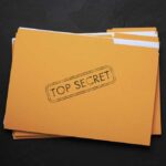 Yellow folder labeled Top Secret on black background.