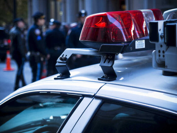 shutterstock_462697451.jpg featured image Police car lights with officers blurred in background.