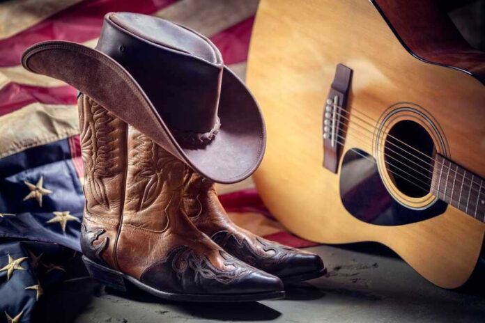 shutterstock_2040537161.jpg featured image Cowboy boots and hat with guitar and flag.
