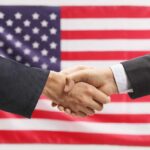 Two hands shaking in front of American flag