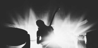 Silhouetted guitarist performing on stage with dramatic lighting.