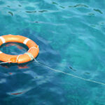Orange life ring floating in clear blue water.