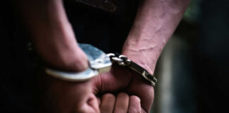 Close-up of hands in handcuffs behind back.