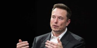 Elon Musk speaking and gesturing with hands in discussion.