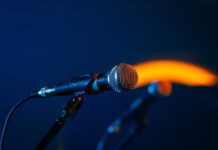 Close-up of a microphone on a stand, dark background.