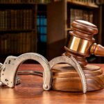 ICE Facility ATTACK in Texas Leads to ARRESTS – Watch Wooden gavel and handcuffs on a table.