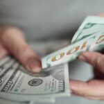 $500K LIFEGUARD Pay Shock in L.A. Hands holding stack of one hundred dollar bills