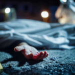 Crime scene with covered body and hand exposed