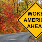 Illegal Alien’s Release Sparks National Debate Yellow road sign Woke America Ahead in autumn forest