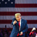 A New Weapon: TRUMP’s Fentanyl Act Donald Trump pointing with large American flag backdrop.