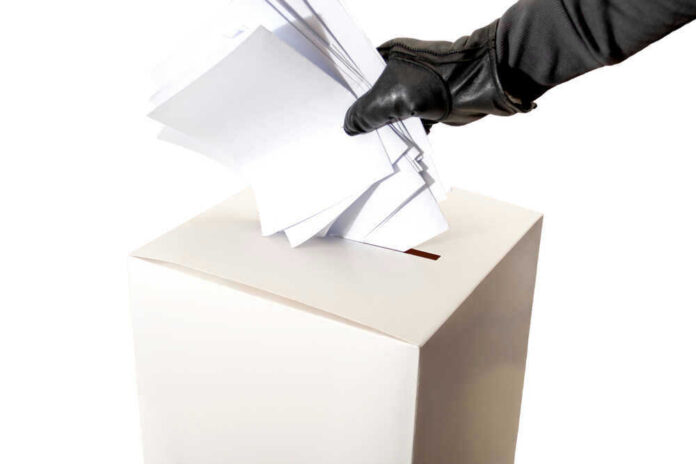 Gloved hand placing multiple papers in a ballot box