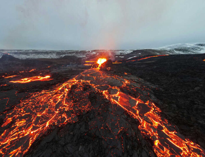 shutterstock_1958468116.jpg Lava flowing from volcanic eruption under gray sky