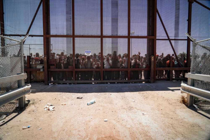 People standing behind a fence on a dusty path