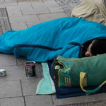 VIDEO: Bloodbath at Homeless Camps; Liberal Policies Exposed Person sleeping on pavement in a blue sleeping bag