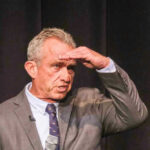 Kennedy Drops the Hammer — Big Pharma PANICS Robert F Kennedy in gray suit shielding eyes.