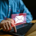 New Emails Expose Fauci’s Shocking Deception Person typing on laptop with mail warning icons.