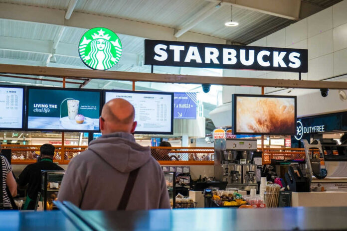 shutterstock_2497511687.jpg Starbucks counter in busy airport shopping area
