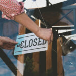Bankruptcy: Iconic American Business DIES Person flipping closed sign on glass door