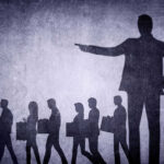 Holiday MASSACRE Will Target American Workers Shadows of laid-off workers walking, large figure pointing