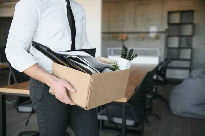 Person carrying box of office supplies in workspace.
