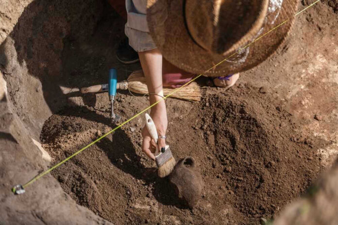 Archaeologist uncovering pottery at a dig site