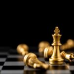 A golden chess king surrounded by fallen pieces on a chessboard
