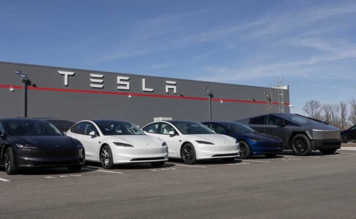 shutterstock_2592566361.jpg A lineup of Tesla cars parked in front of a Tesla building