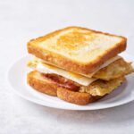 A stacked sandwich with toasted bread, cheese, and egg layers