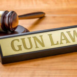 Supreme Court Gun Rights BOMBSHELL A gavel and a nameplate reading GUN LAW on a wooden surface