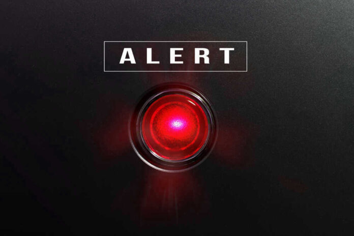 Red alert light against black background, text ALERT