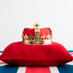It’s Official: Prince BANISHED A royal crown resting on a red velvet pillow with a British flag background