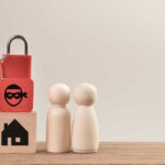 A padlock with keys next to wooden blocks and two figurines