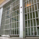 Gang Leader Gets LIFE — Missionary Hostage Horror Empty prison cell with metal bars and toilet.