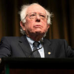 Bernie Sanders Slams AI Job Apocalypse Bernie Sanders in suit speaking at podium.