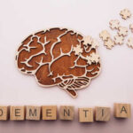 New Blood Test PREDICTS Dementia 25 Years Early Wooden brain illustration with puzzle pieces and the word DEMENTIA spelled out in blocks