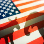 GOP Power Play Hands Democrats Election Goldmine Donkey and elephant shadows on American flag background.