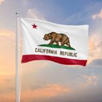 California state flag waving against a sunset sky