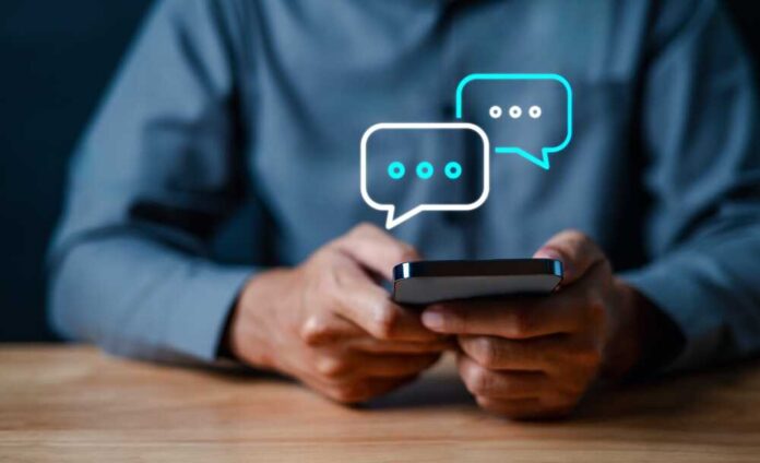 shutterstock_2402269631.jpg Person holding a smartphone with chat bubbles above