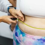 Needle-Free Weight Loss Breakthrough A person measuring another's waist with a tape measure