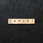 Wooden letters spelling the word 'Cancer' on a black textured background