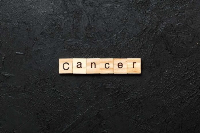 Wooden letters spelling the word 'Cancer' on a black textured background