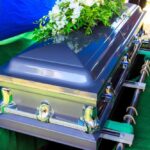 Totalitarian Fighter DIES — Free Speech Movement Mourns A silver casket adorned with flowers at a gravesite