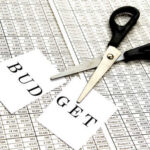 Budget Flyers LOSE Everything Scissors cutting a paper labeled 'BUDGET' on a financial spreadsheet