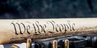 Gun, bullets, Constitution scroll on American flag.