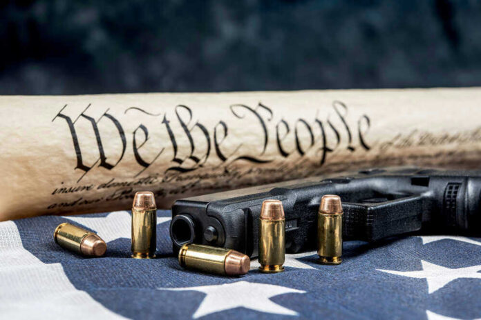 Gun, bullets, Constitution scroll on American flag.