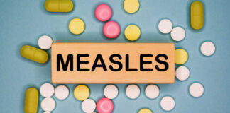 Wooden block with the word 'MEASLES' surrounded by various pills