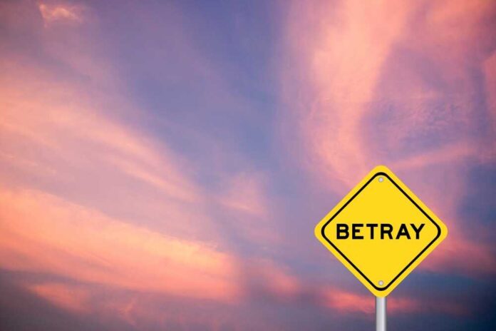 A yellow warning sign with the word 'BETRAY' against a colorful sunset sky