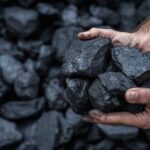 Energy Shake-Up: Billions Redirected to Coal! Hands holding several pieces of black coal against a background of more coal